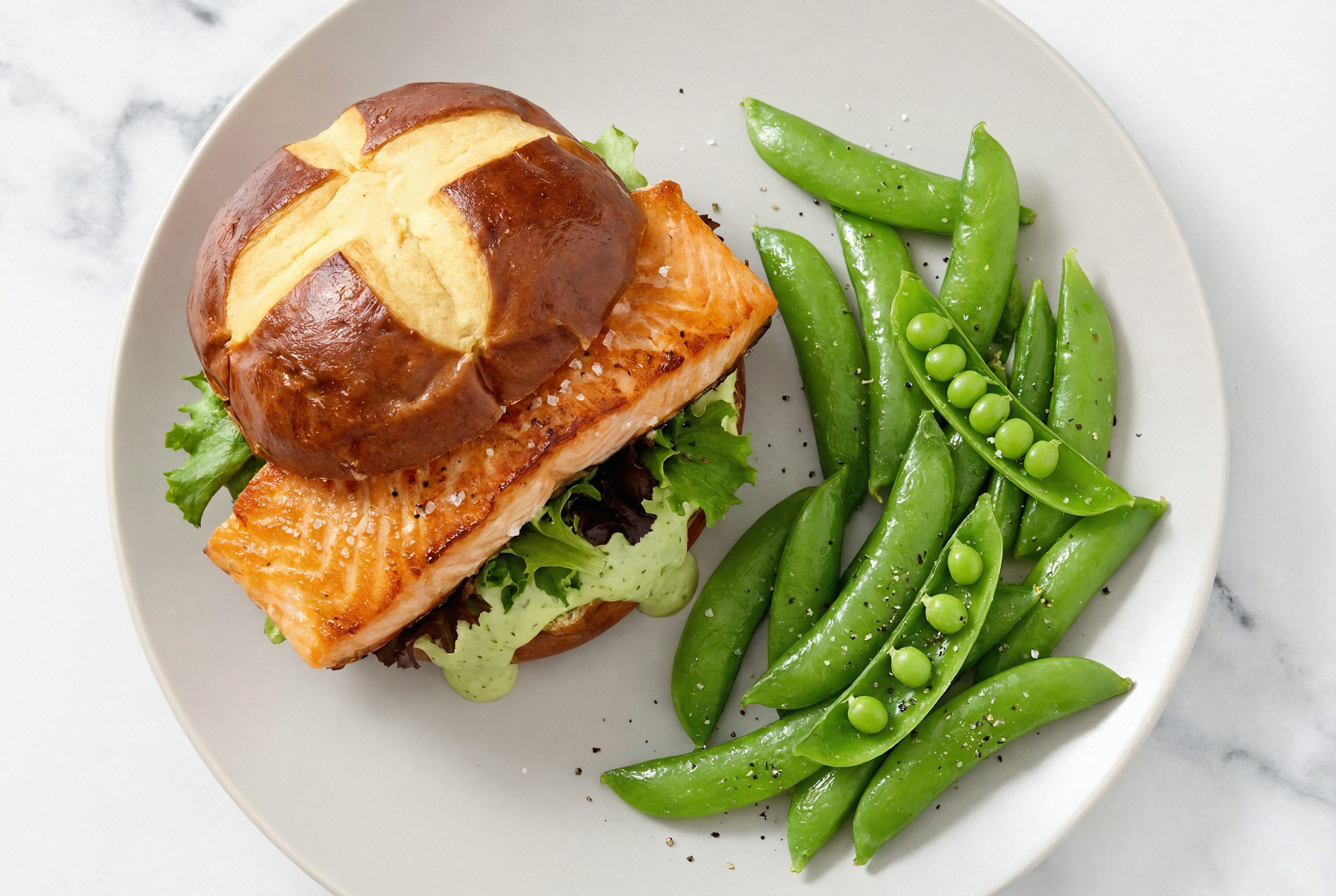 Green Goddess Salmon Sandwich on Pretzel Bun with Spring Mix + Snap Peas